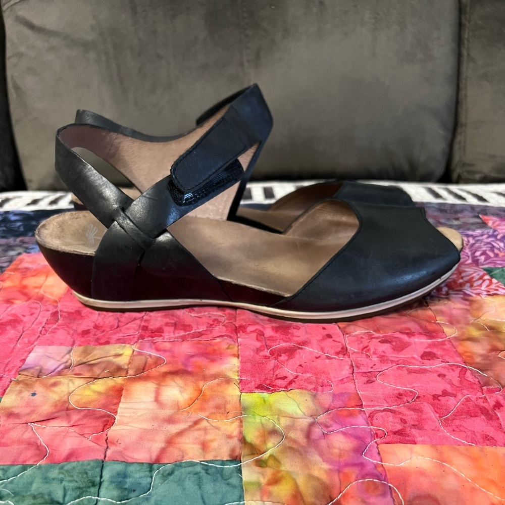 Dansko black leather wedge sandals with Velcro closure on ankle strap.